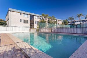 a large swimming pool in front of a building at The Dunes Two bedroom apartment overlooking pool in Fingal Bay
