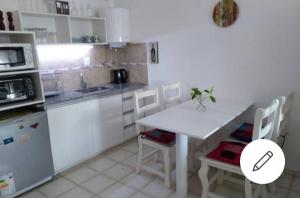 - une cuisine blanche avec une table et des chaises blanches dans l'établissement Cómo en casa Monoambiente, à Córdoba