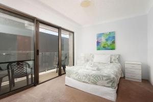 a white bedroom with a bed and a balcony at Great Location in Nelson Bay in Nelson Bay