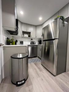 a kitchen with a stainless steel refrigerator and a trash can at Private Cozy Secondary Suite, 2 Bedrooms, Separate Entrance in Calgary