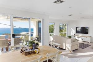 een woonkamer met een tafel, stoelen en een televisie bij Tranquil with Harbour Views in Nelson Bay
