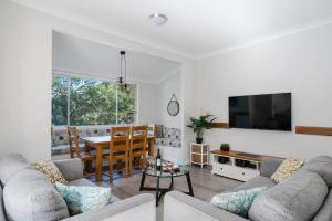 uma sala de estar com um sofá e uma mesa em Coal and Candle by Beach Stays em Berowra