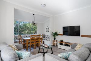 a living room with a couch and a table at Coal and Candle by Beach Stays in Berowra