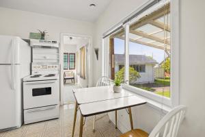 eine Küche mit einem Tisch und einem weißen Kühlschrank in der Unterkunft Coastal Chic Retreat by Iris Properties! in Victoria