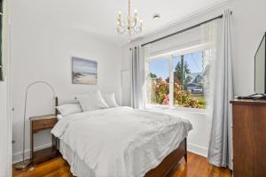 a white bedroom with a bed and a window at Coastal Chic Retreat by Iris Properties! in Victoria