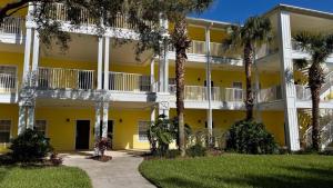 ein gelbes Gebäude mit Palmen davor in der Unterkunft Beautiful 3 Bedroom Apartment minutes from Disney! in Kissimmee