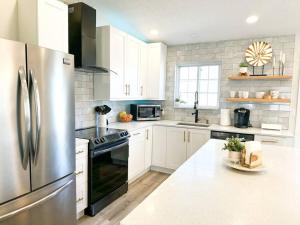 a kitchen with white cabinets and a stainless steel refrigerator at Modern and Spacious Home near downtown and UNL in Lincoln