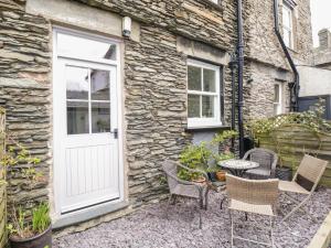 uma casa de pedra com uma porta branca e cadeiras em Lamb Cottage em Windermere