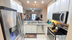 a kitchen with white cabinets and a stainless steel refrigerator at Beautiful 3 Bedroom Apartment minutes from Disney! in Kissimmee