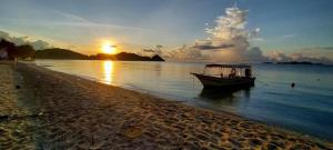 a boat sitting on the water near a beach at Redang Campstay A Frame in Redang Island
