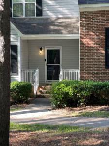 ein Haus mit einer Veranda und einem Backsteinhaus mit einer Tür in der Unterkunft Full house charm mins frm DT Raleigh, NC State University in Raleigh