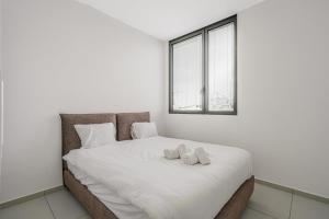 um quarto com uma grande cama branca e 2 almofadas em Modern 2BR Idelson Street By Holiday Rentals em Tel Aviv