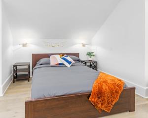 een slaapkamer met een bed met een oranje deken erop bij Modern Tudor Style Carriage House - Patio & grill in Ann Arbor