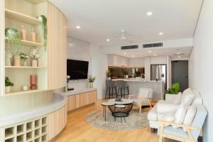 a living room with white furniture and a kitchen at Ultimate Riverview Designer 2BD Apartment at CBD in Brisbane