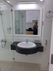 una mujer tomando una foto de un lavabo en un baño en căn hộ OCEANVISTA en Ấp Phú Tịnh (2)