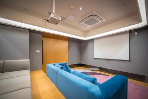 Tulu Apartment Shanghai Xuhui في شانغهاي: غرفة معيشة بها أريكة زرقاء وجهاز عرض