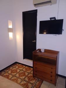 a room with a door and a dresser and a television at HOSTEL M&H in Cartagena de Indias