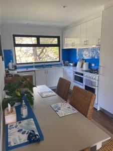 a kitchen with a table and chairs and a kitchen with blue at Refuge Cove On Pittwater in Clareville