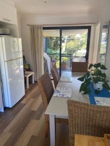 a kitchen and dining room with a table and a refrigerator at Refuge Cove On Pittwater in Clareville