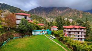 a group of buildings in a field with mountains at Gagan Resorts in Dharamshala