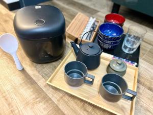 a coffee maker and four cups on a wooden tray at May2023 New Open! The Hotel SPACE 下北沢 in Tokyo