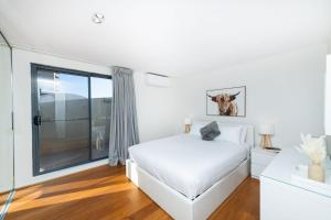 a white bedroom with a bed and a window at Griffin 184 Kingston Apartment in Kingston 