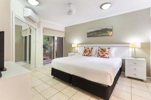 a bedroom with a large bed and a tv at Coral Horizons - Beachfront apartments in Palm Cove