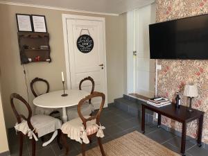 een woonkamer met een tafel en stoelen en een televisie bij Pia’s Country House in Båstad