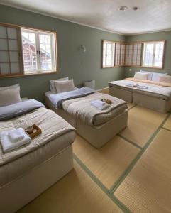 Zimmer mit 3 Betten und Fenstern in der Unterkunft Myoko Forest Lodge in Myōkō