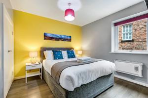 a bedroom with a large bed and a yellow wall at Host & Stay - Campbell Square Roof Terrace Apartment in Liverpool