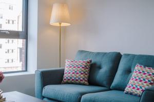 Sofá azul sentado en una sala de estar con lámpara en Host & Stay - The Roscoe Nest en Liverpool
