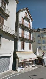 a white building with balconies and a store at Chez Marie et Didier Chalet saint Jacques in Lourdes