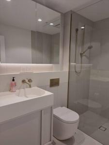 y baño con aseo, lavabo y ducha. en Sapphire Royale Suite in Macquarie Park en Sídney