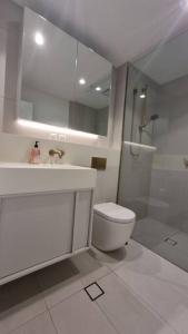 a bathroom with a toilet and a sink and a shower at Sapphire Royale Suite in Macquarie Park in Sydney