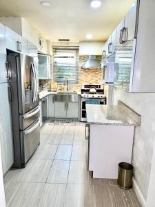 a large kitchen with stainless steel appliances and wooden floors at LGA airport 3 mins, 3 BR duplex plus Parking and private backyard, 9mins subway! in East Elmhurst