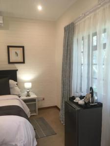 a bedroom with a bed and a window with curtains at Green Gables in Johannesburg