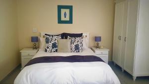 a bedroom with a white bed with two nightstands and two lamps at Green Gables in Johannesburg