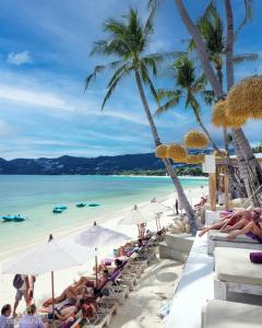 a group of people sitting on a beach with umbrellas at Elephant Beach Club & Resort Samui in Chaweng