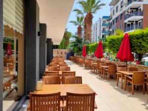 een rij tafels en stoelen met rode parasols bij Altinersan Hotel in Didim