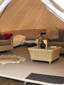 une tente avec un lit, un canapé et une table dans l'établissement Old Oak Farm, 