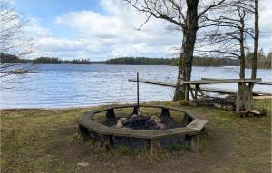 a fire pit in the grass next to a lake at 1 Bedroom Nice Home In Jälluntofta in Jälluntofta +14 photos