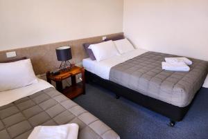 NanangoにあるNanango Star Motelのベッド2台、テーブル(ランプ付)が備わる客室です。