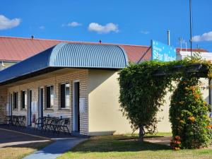 een gebouw met een blauwe luifel en een boom bij Nanango Star Motel in Nanango