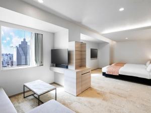 a white bedroom with a bed and a tv at Daiwa Roynet Hotel Nagoya Shinkansenguchi in Nagoya