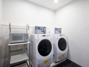 a laundry room with two washing machines and a microwave at Daiwa Roynet Hotel Nagoya Shinkansenguchi in Nagoya