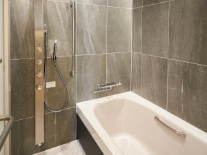 a bathroom with a shower and a bath tub at Daiwa Roynet Hotel Nagoya Shinkansenguchi in Nagoya