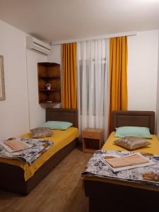 two beds in a room with orange curtains at Sobe Nedović in Budva