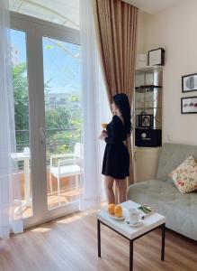 a woman standing in a living room looking out a window at CHEZ LOTUS VN in Ho Chi Minh City