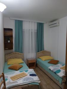 two beds in a room with green curtains at Sobe Nedović in Budva