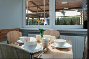 a wooden table with white dishes and flowers on it at Villa Krotoszyce in Krotoszyce